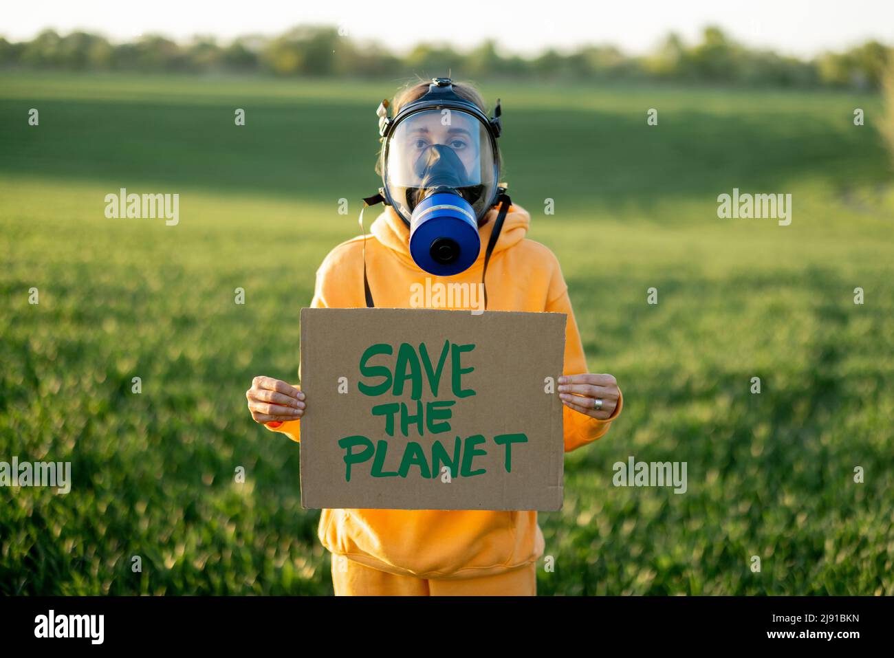 Person in Gasmaske hält Pappe mit einem Aufruf, den Planeten zu retten Stockfoto