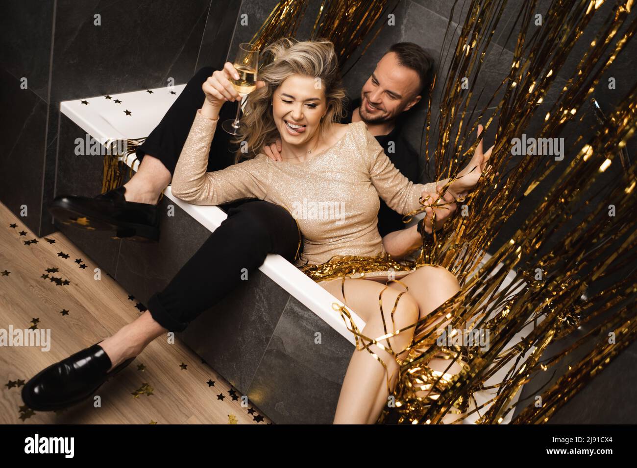 Romantisches Paar lächelnden Mann, blonde Frau Zunge aus feiern 30 Jahre Jubiläum. In der Badewanne liegend sitzen. Lametta Stockfoto