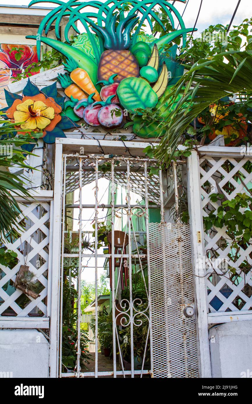 Ein eingezäunter Eingang mit einem farbenfrohen Kunstwerk aus farbenfrohen tropischen Früchten und Gemüse entlang der Straße in Nassau, den Bahamas. Stockfoto