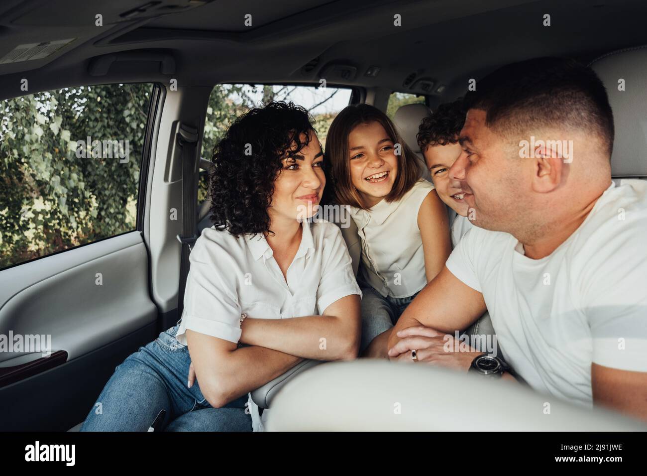 Mutter und Vater mit zwei Teenagekindern auf Wochenend-Roadtrip, Happy Four Mitglieder Familie auf Reisen mit dem Minivan Auto Stockfoto
