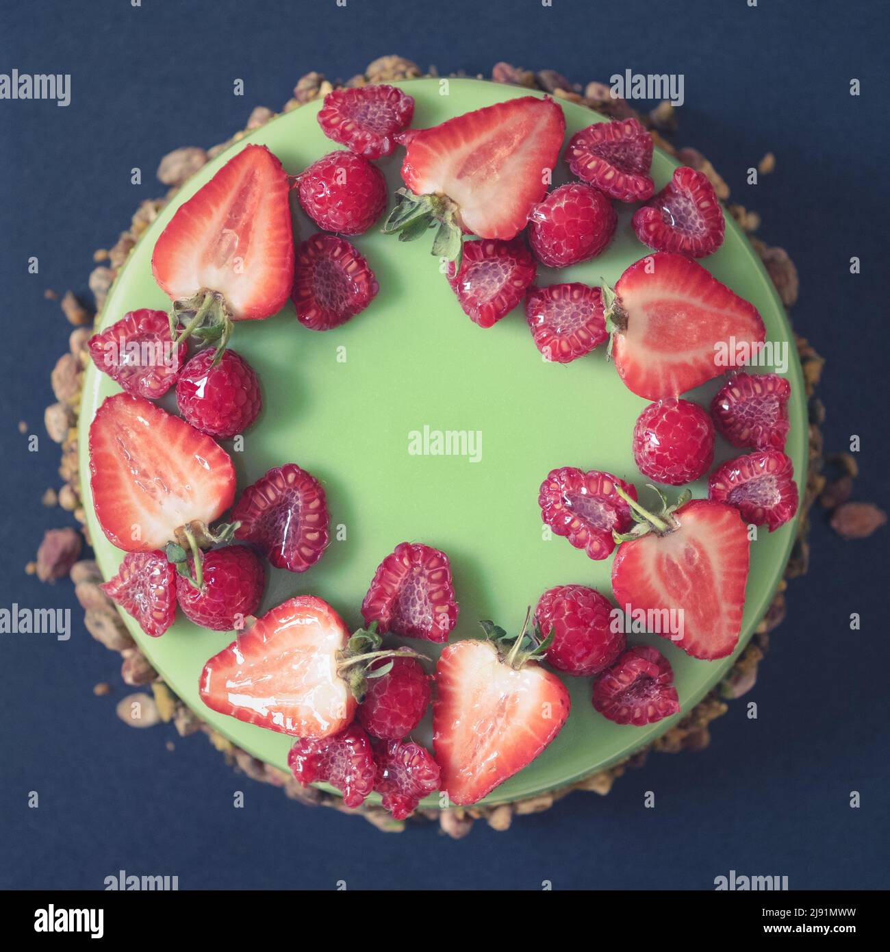Eine wunderschöne Pistachio-Geburtstagstorte, gekrönt mit frischen Erdbeeren und Himbeeren Stockfoto