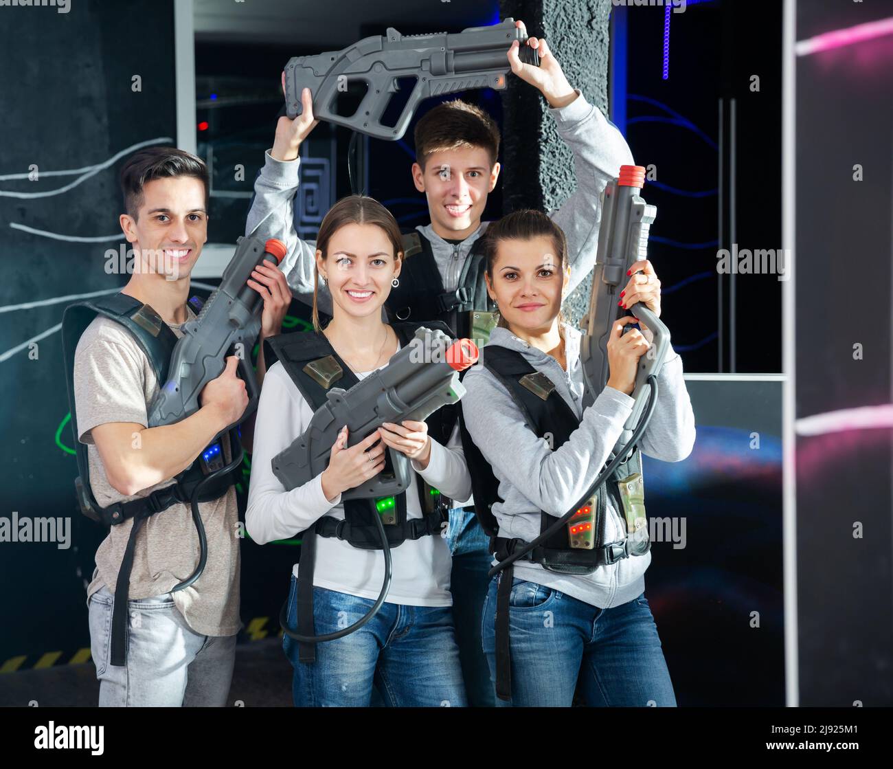 Group Portrait von Freunden Mädchen und Jungs mit Gewehren in den Händen in dunklen Laser tag Zimmer Stockfoto