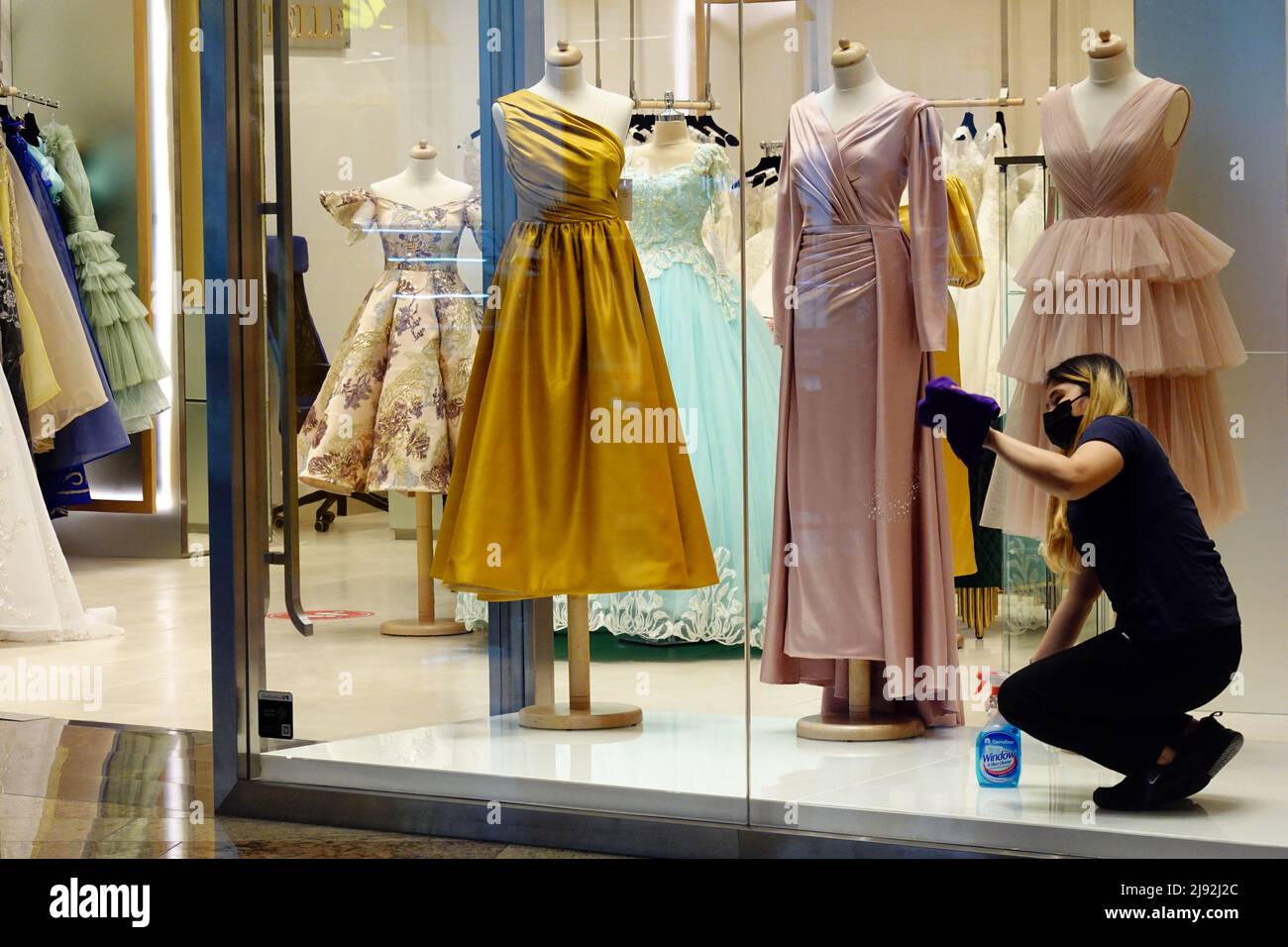26.03.2021, Dubai, , Vereinigte Arabische Emirate - Verkäuferin reinigt die Fenster eines Modehauses aufgrund von Kundenmangel in Zeiten der Corona-Pandemie. 00S Stockfoto