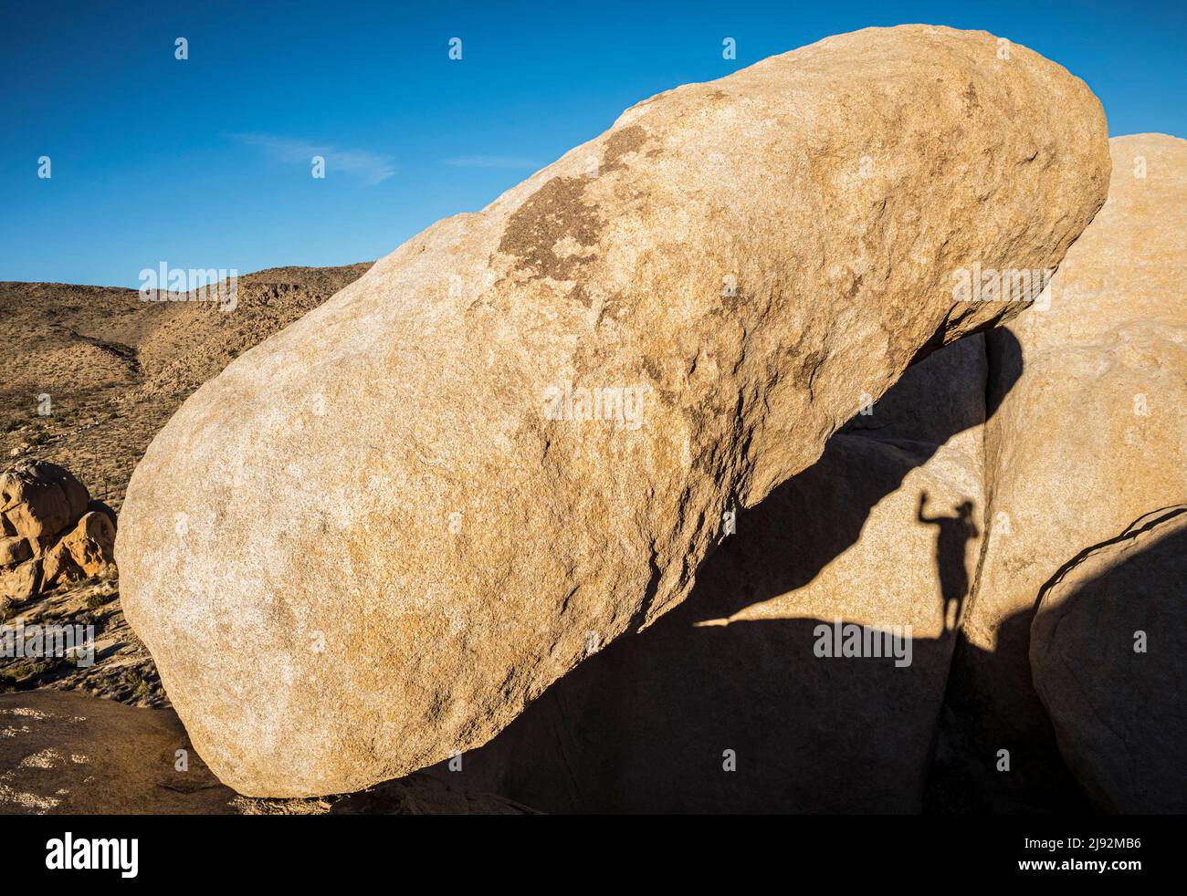 Ein Fotograf schattet Selfie, während er über Felsformationen im Joshua Tree National Park klettert. Stockfoto