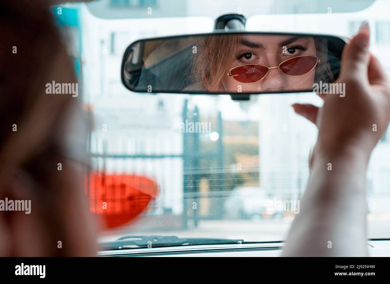 Rückansicht der Person nicht-binäre junge Fahren ein Auto Blick in den Rückspiegel. Hochwertige Fotos Stockfoto