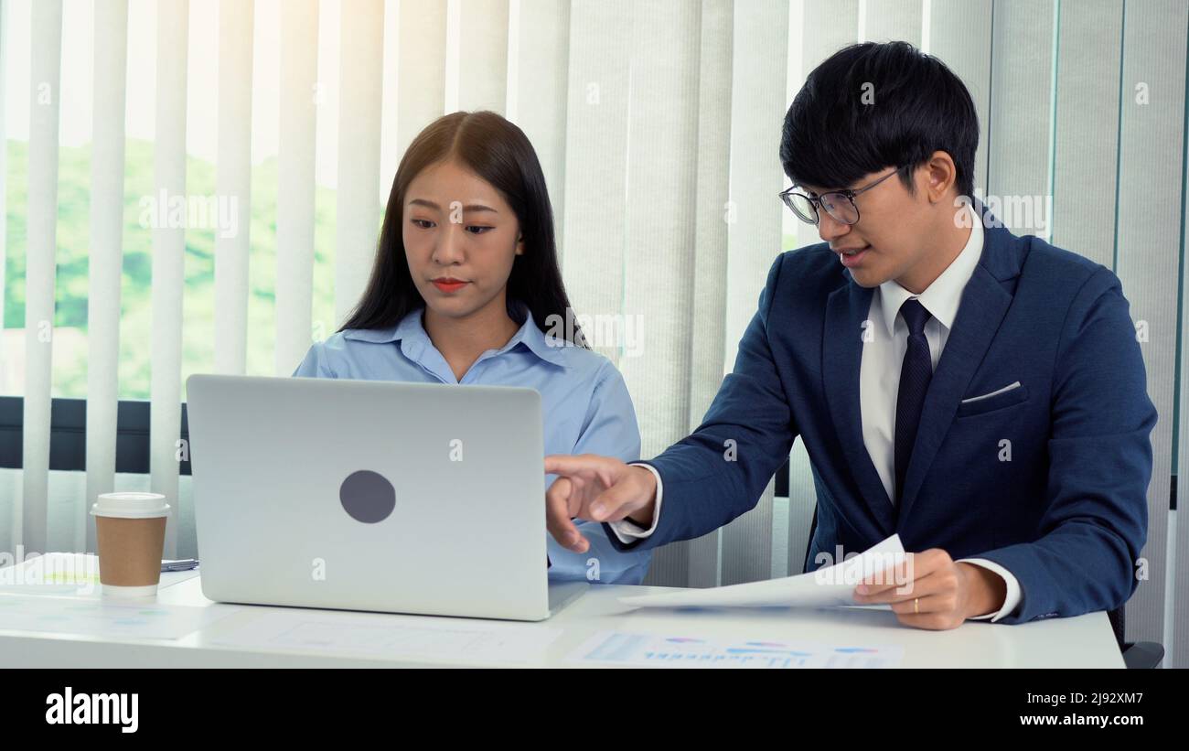 Zwei asiatische Geschäftsleute arbeiten zusammen und analysieren die Daten am Computer. Stockfoto