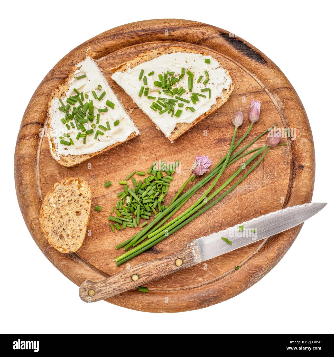 Vollkornbrotscheiben mit Frischkäse, grünem gehacktem Schnittlauch, Pfeffer und Salz auf einem auf Weiß isolierten Holzschneidebrett Stockfoto