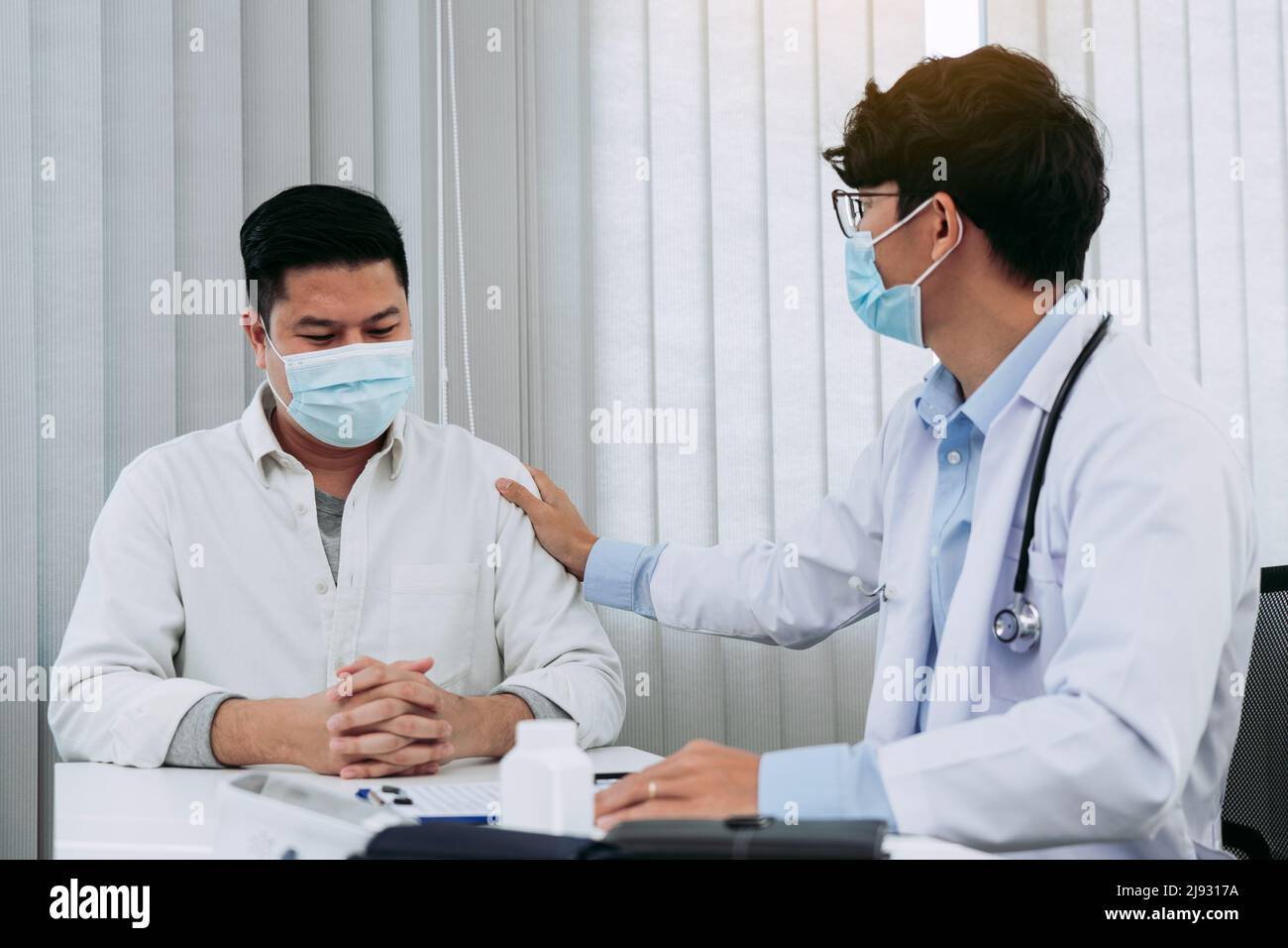 Der Arzt nahm sich Trost im Arm des Patienten, um die Krankheit zu erklären. Stockfoto