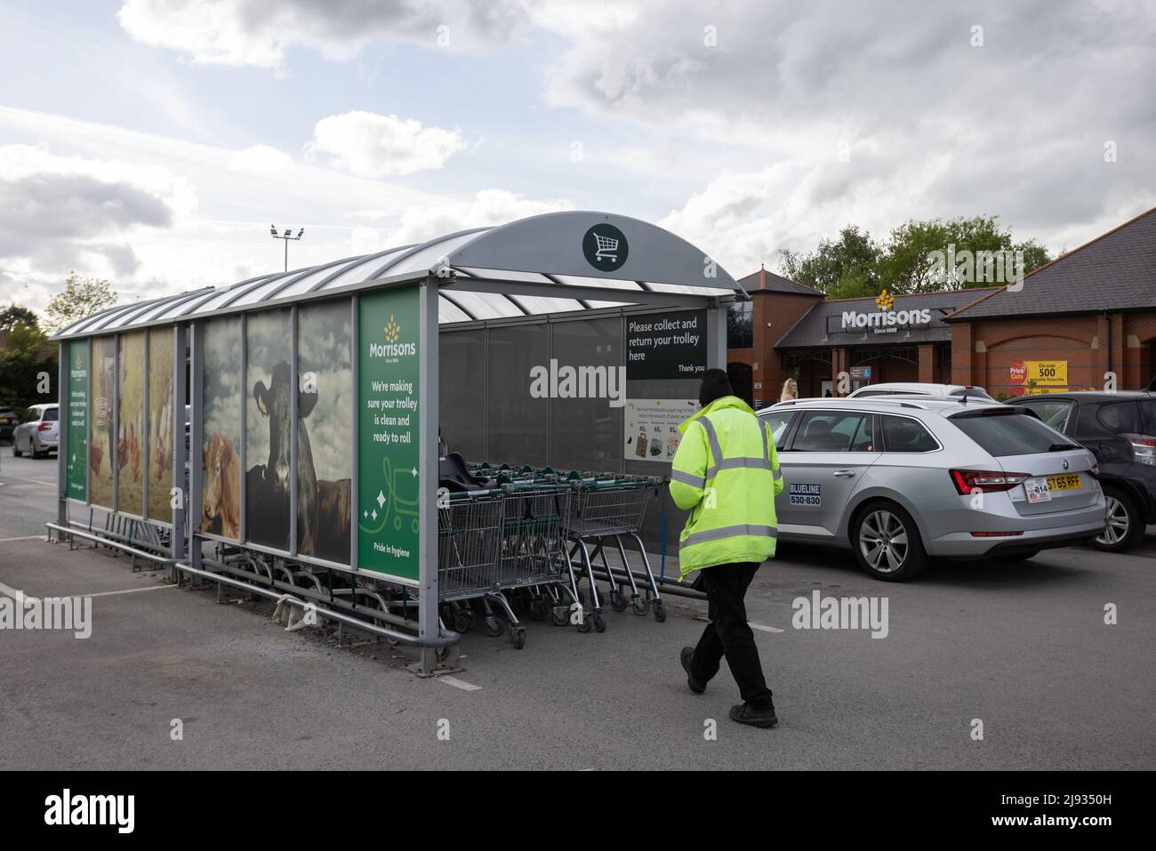 Mann in gelber reflektierender Weste schiebt Einkaufskörbe in Bucht am Morrisons Supermarkt Starbeck Store Parkplatz Stockfoto