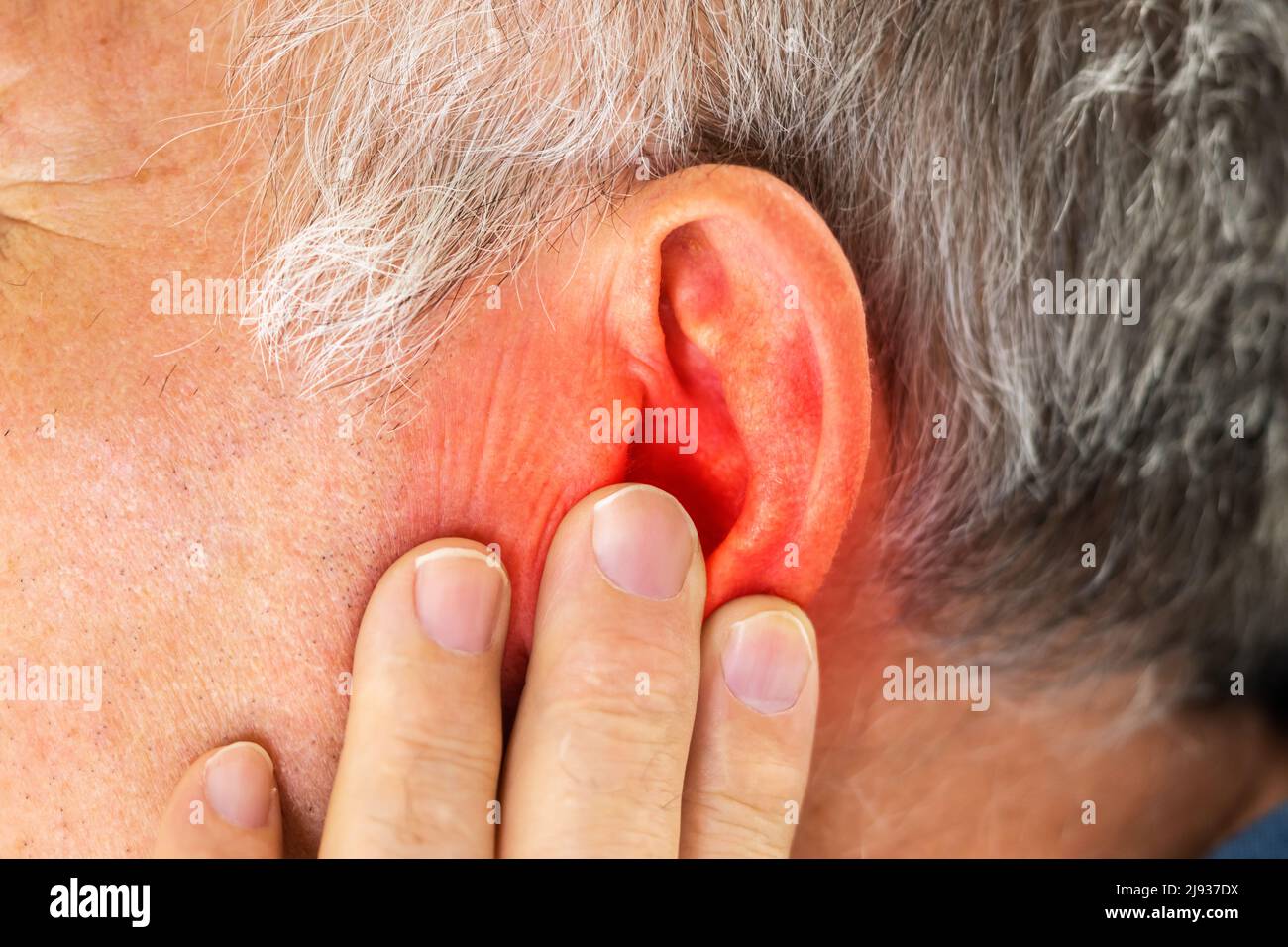 Nahaufnahme der Mann für Ohr mit Hand auf grauem Hintergrund Stockfoto