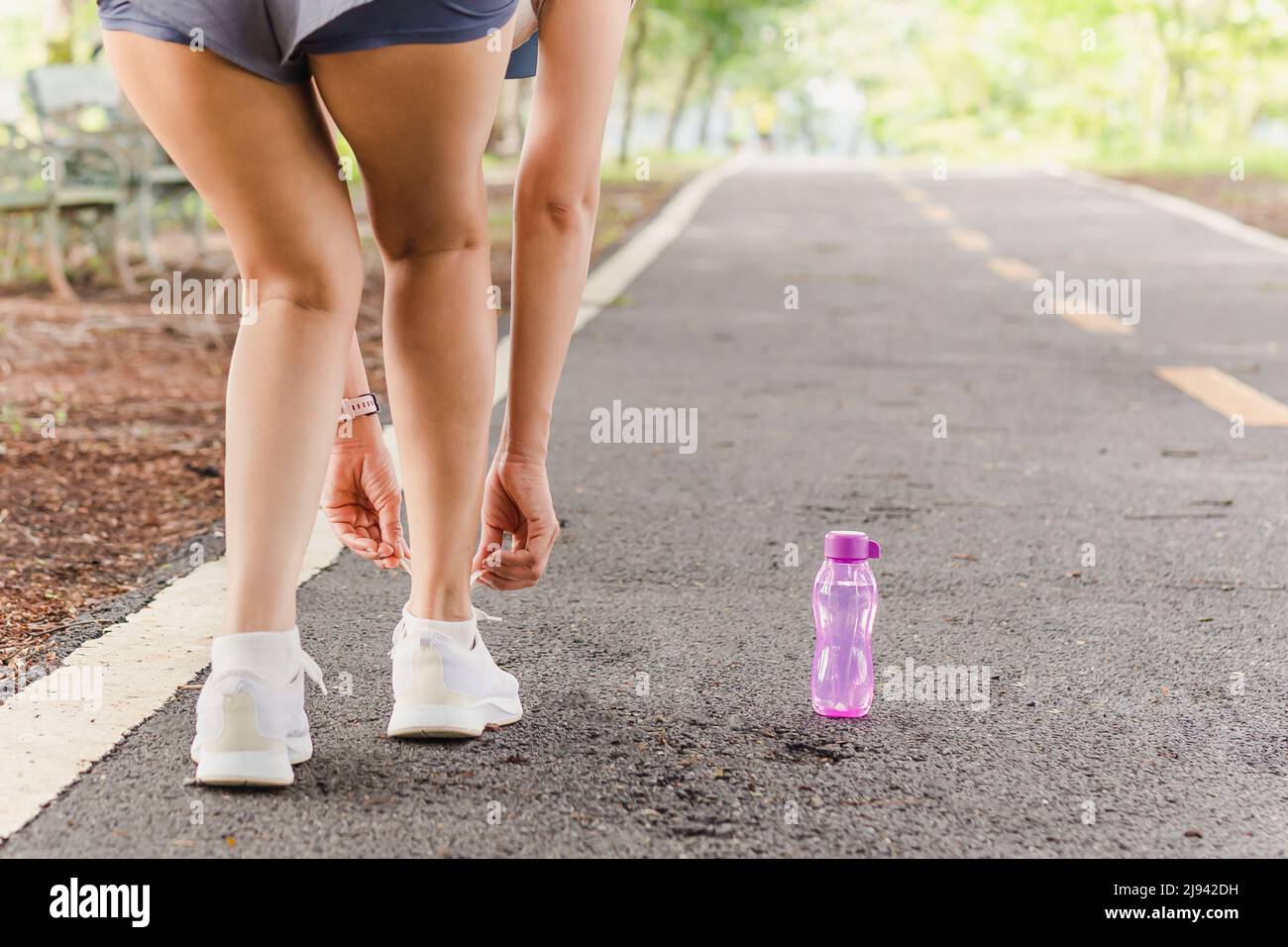 Frau schnürt ihre Schnürsenkel vor dem Training im Park. Stockfoto