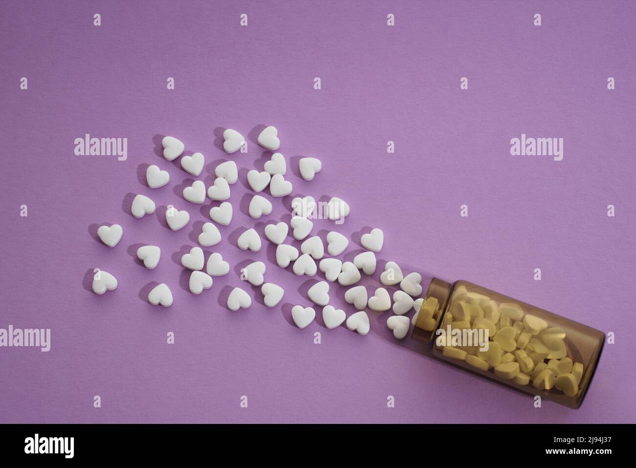 Draufsicht auf verschüttete Herzform Pillen Flasche auf lila Hintergrund Stockfoto