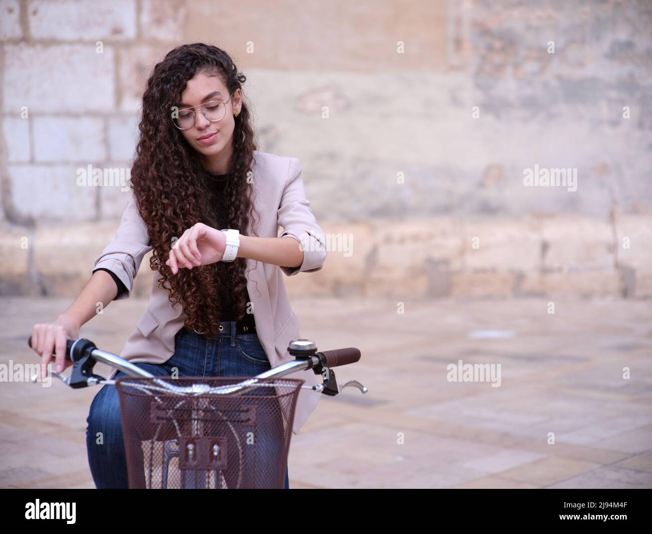 eine arabische Frau, die mit einem umweltfreundlichen Fahrzeug in einer Cafeteria arbeitet, blickt auf die Zeit auf ihrer Uhr, Vorderansicht Stockfoto