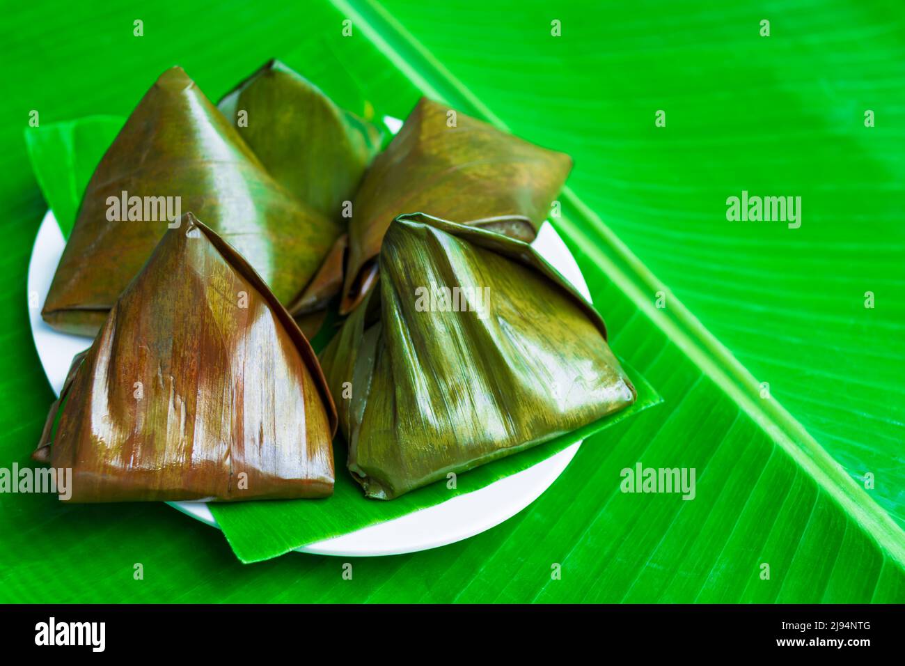 Malaysische Delikatessen Kuih Koci im Bananenblatt isoliert über dem grünen Bananenblatt. Stockfoto