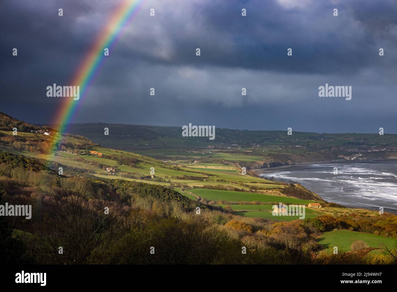 Stürmisches Wetter und ein Regenbogen über Robin Hood's Bay aus Ravenscar, North Yorkshire, England, Großbritannien Stockfoto