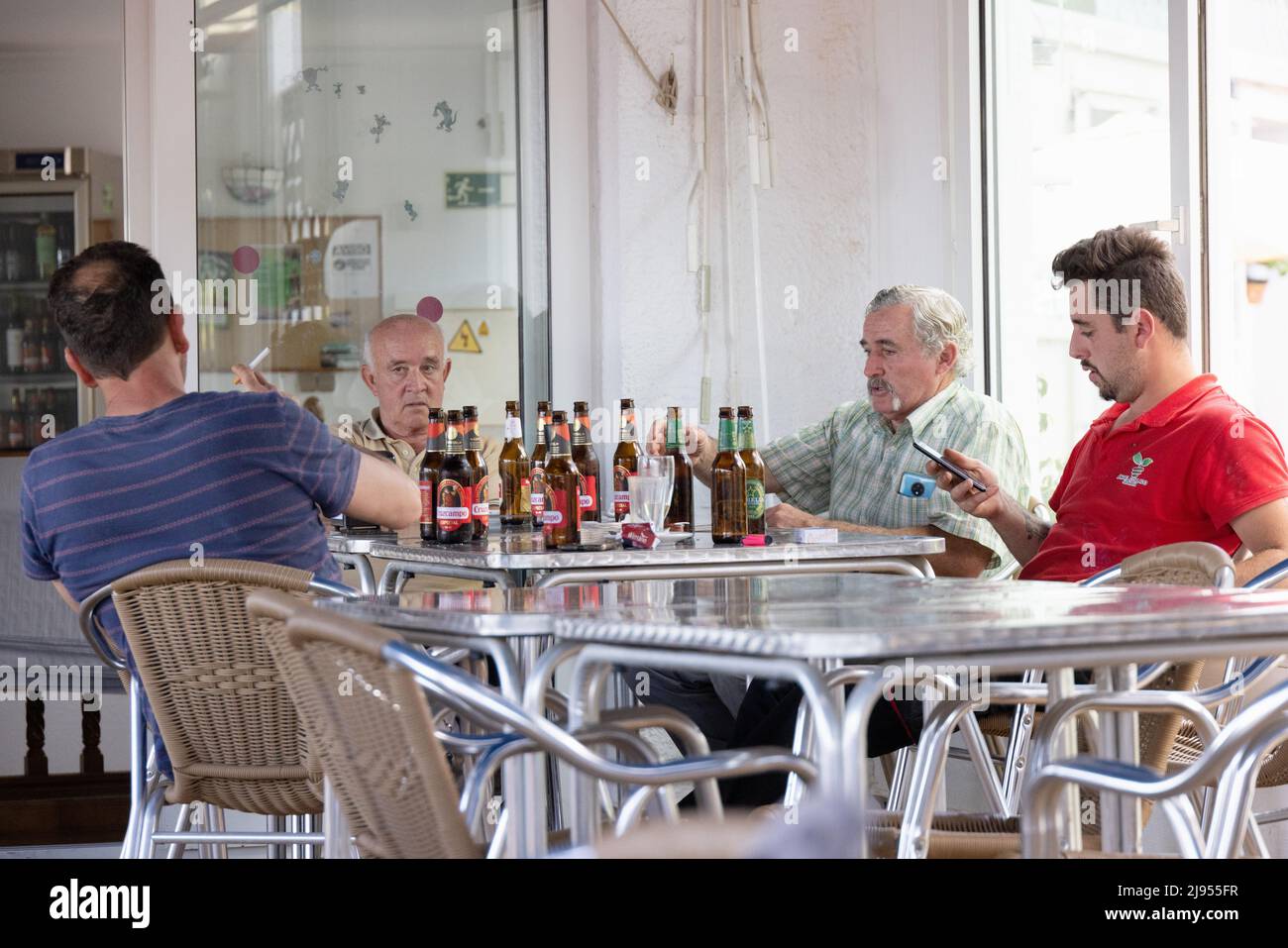 Spanischer Lebensstil; Eine Gruppe von Männern mittleren Alters, die tagsüber an einem Tisch sitzen und in einer Bar Bier trinken, Andalusien, Spanien, Europa Stockfoto