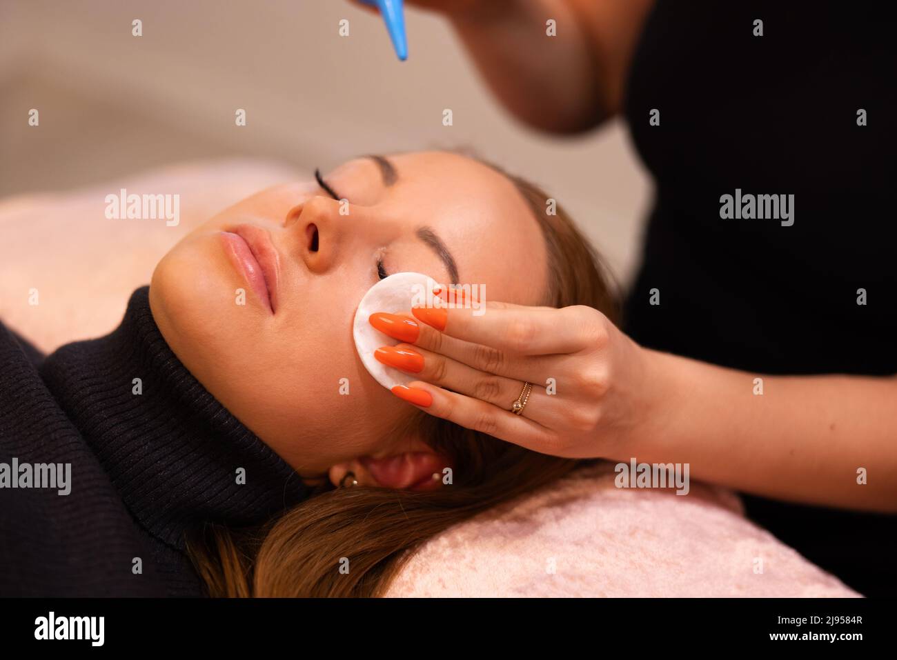 Hands of Beauty Specialist reibt Baumwolle auf das Gesicht des weiblichen Kunden Stockfoto