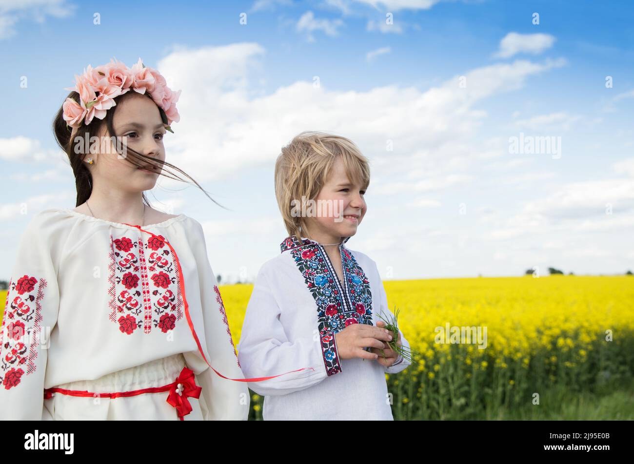 Junge und ein Mädchen in bestickter traditioneller Kleidung vor dem Hintergrund des gelb blühenden Rapsfeldes. Einheit, Unterstützung für die Ukraine. Die Ukrainer sind wieder da Stockfoto