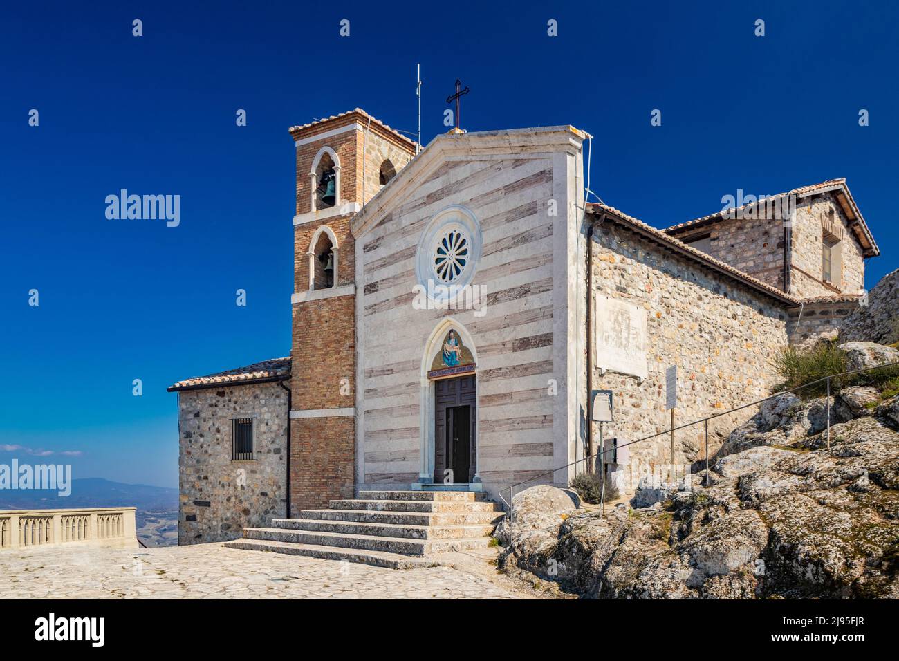 Das kleine Dorf Tolfa, in Latium. Die Wallfahrtskirche der Madonna della Rocca auf der Klippe, wo die Festung steht. Die Fassade mit dem ros Stockfoto