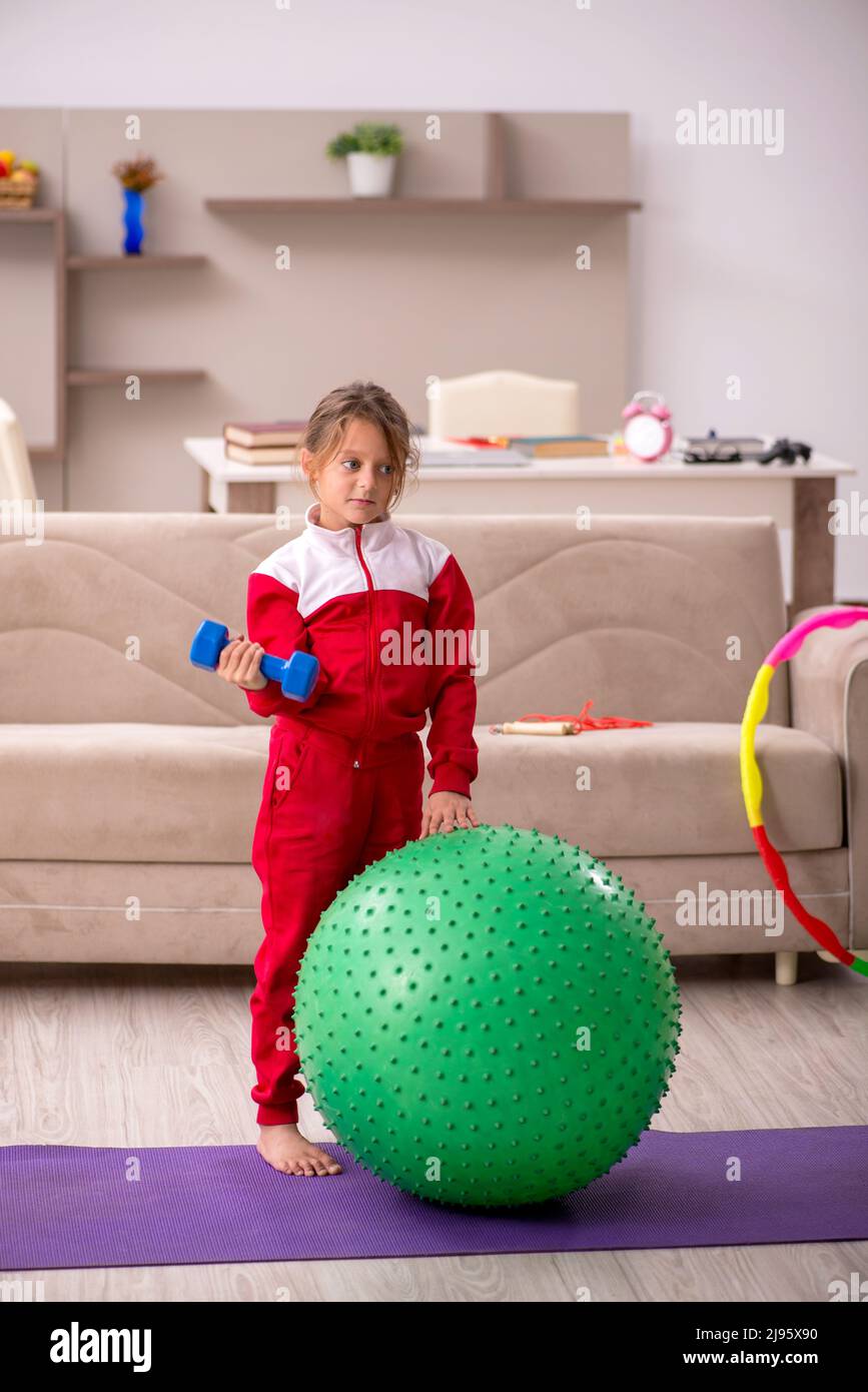 Junges kleines Mädchen, das zu Hause Sportübungen macht Stockfoto