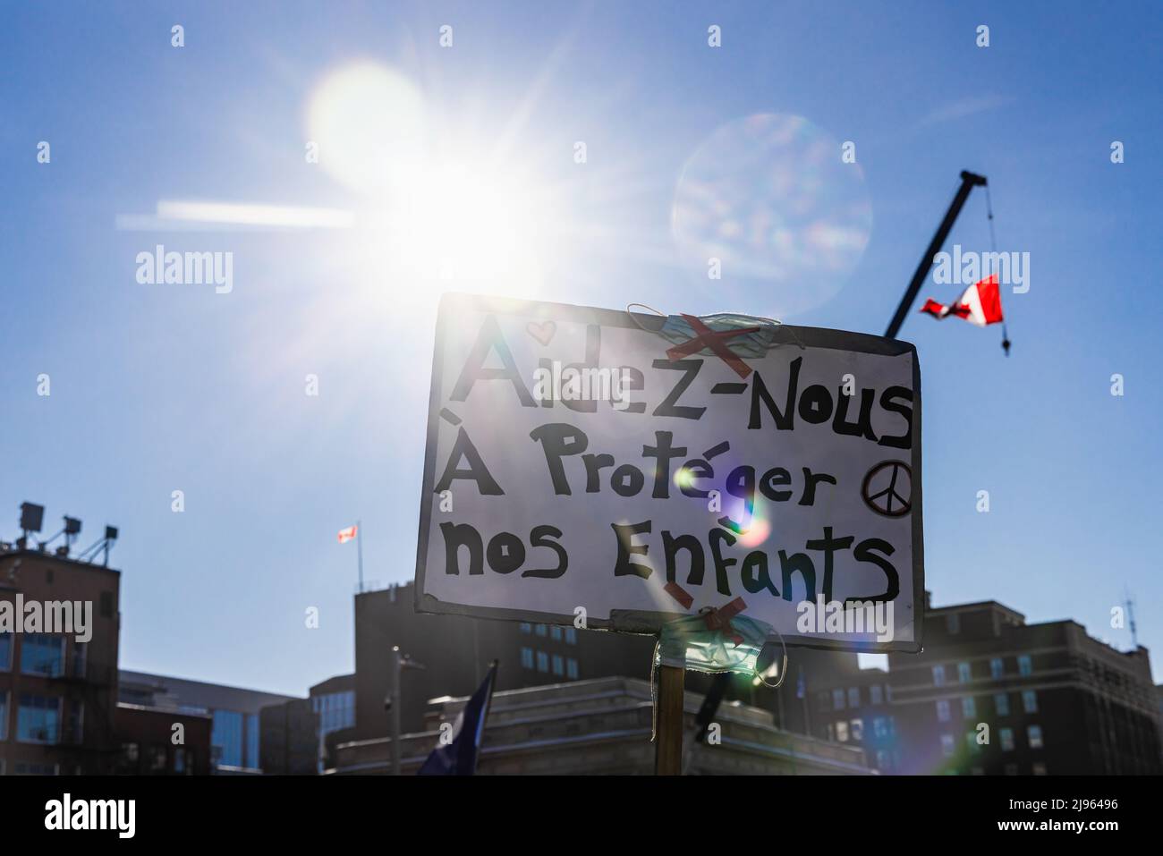 Hintergrundbeleuchtetes Bild mit Streulicht auf einem französischen kanadischen Schild, auf dem steht, dass wir unsere Kinder während einer Demonstration in der Innenstadt gegen Covid 19-Mandate schützen sollen. Stockfoto