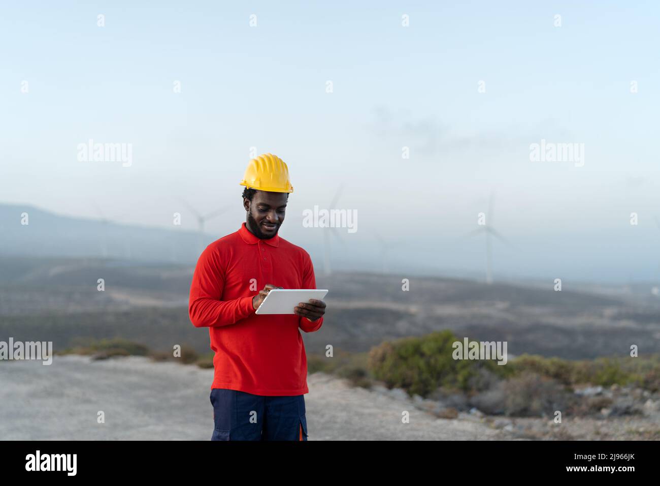 Afrikanischer Ingenieur, der mit Tablet auf der Baustelle arbeitet - Technologie- und Industriekonzept Stockfoto