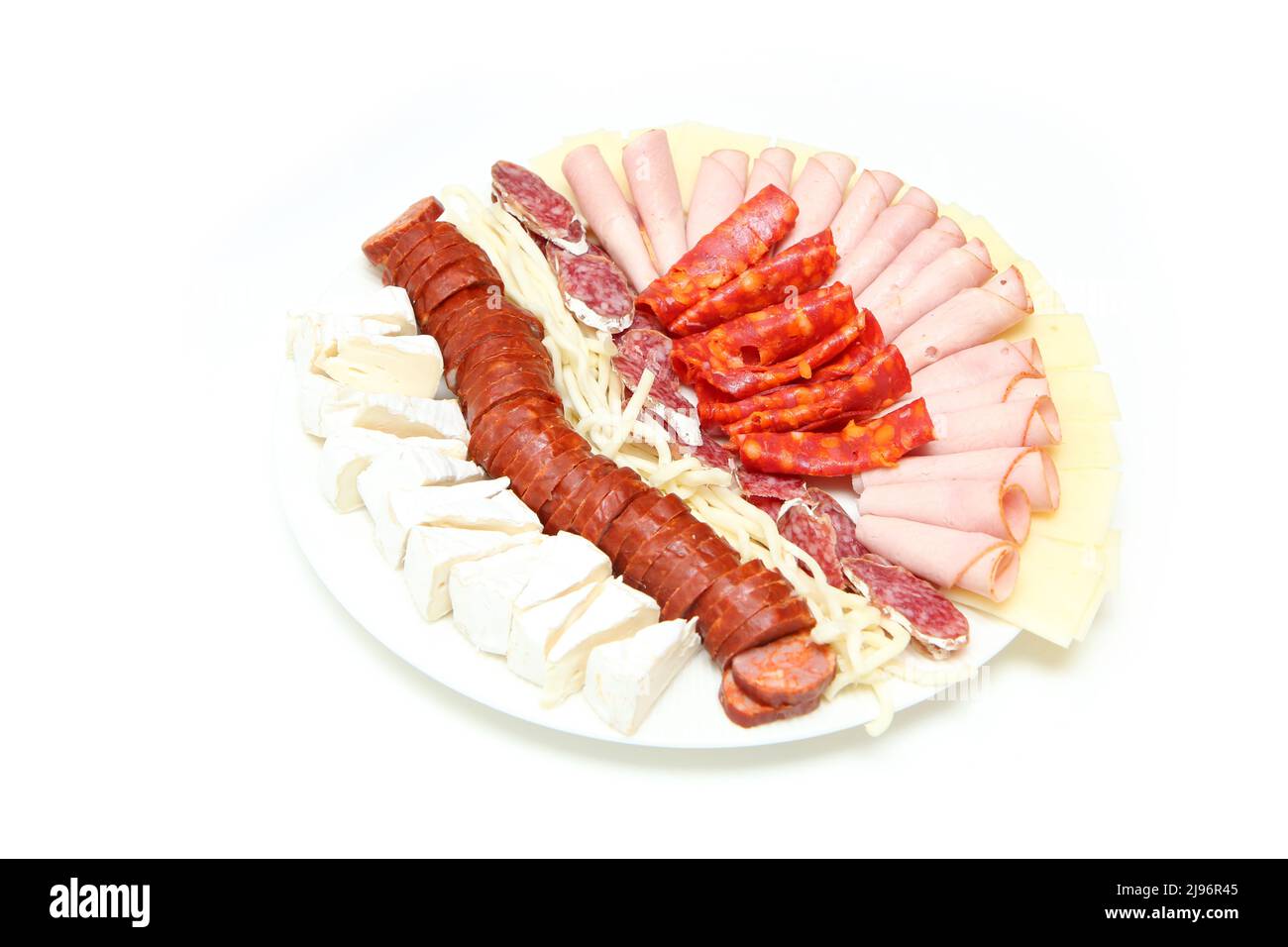 Der Teller mit sortierten Käsesorten und verschiedenen Schinken und Salamis auf weißem Hintergrund isoliert. Stockfoto