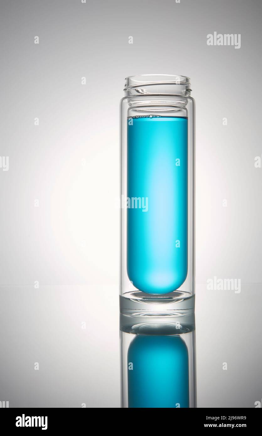 Transparente Glasflasche mit schwarzem Deckel. Mit blauer Flüssigkeit, auf weißem Hintergrund. Stockfoto