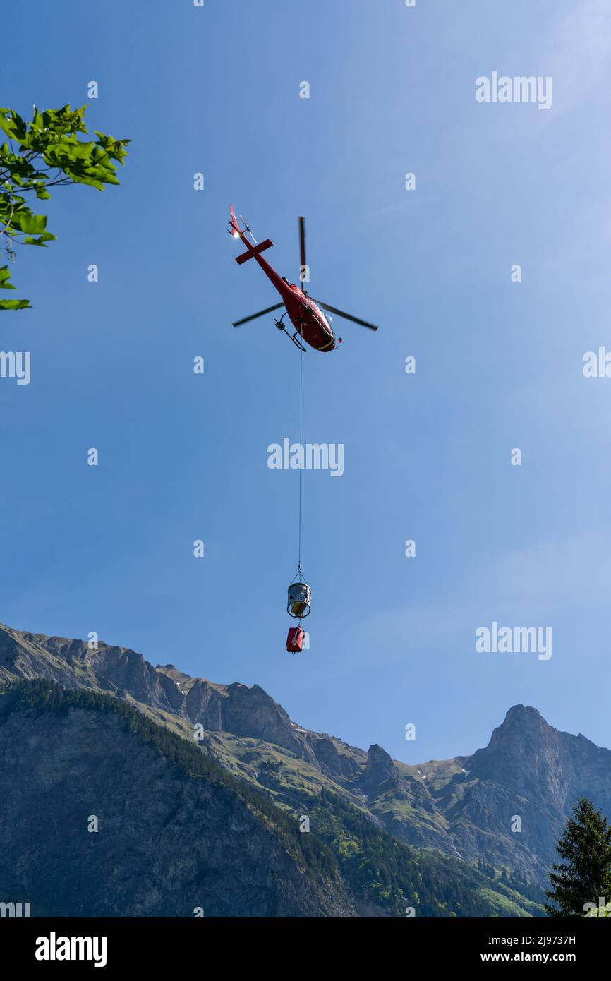 Maienfeld, Schweiz - 20. Mai 2022: Helikopter mit einem Eimer Zement zu einer entfernten Berghütte in den Schweizer Alpen Stockfoto