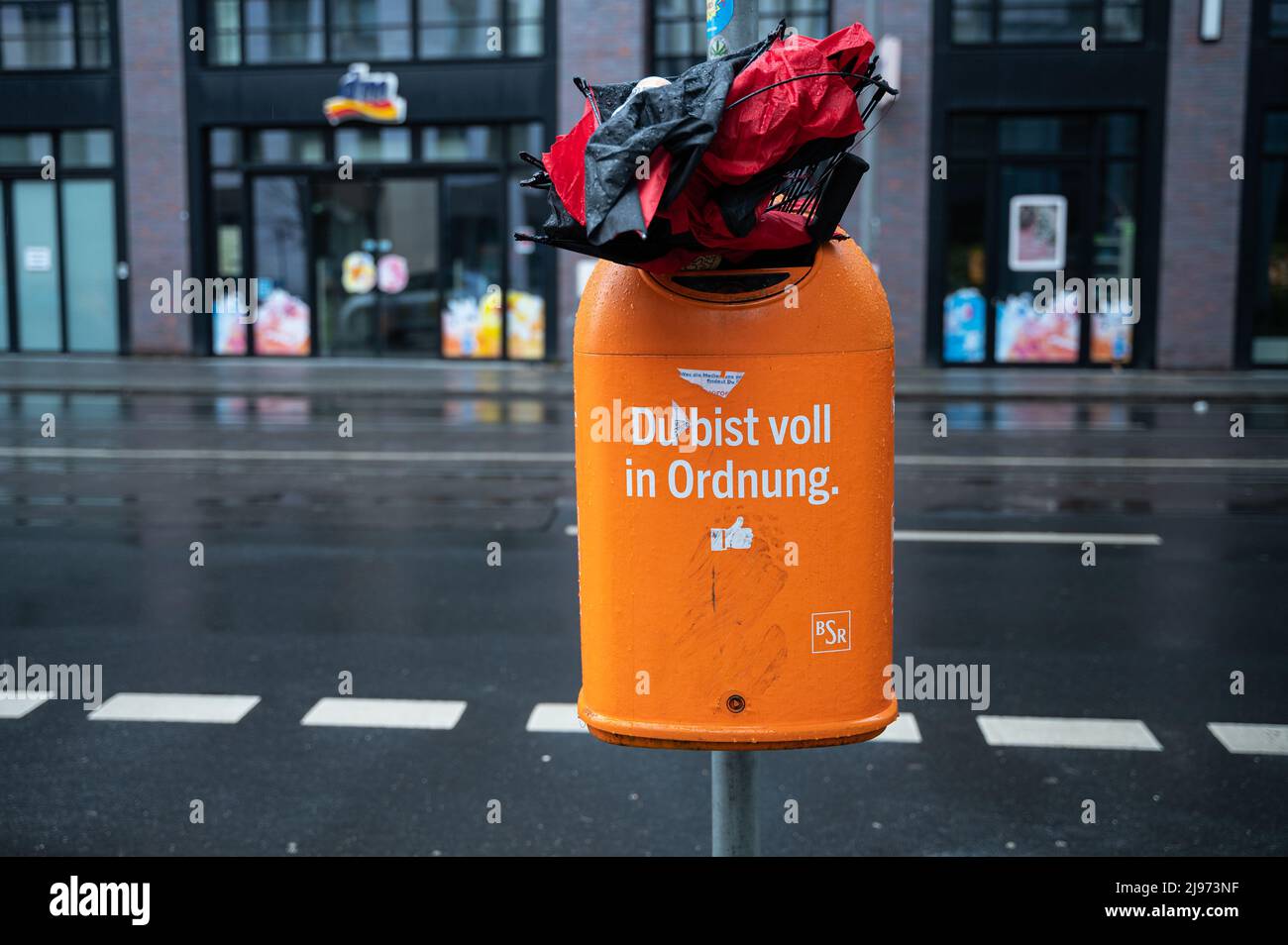 20.02.2022, Berlin, Deutschland, Europa - Ein zerbrochener Regenschirm, der in einen überfließenden Mülleimer der BSR mit der Aufschrift 'Du bist voll in Ordnung' gequetscht wurde. Stockfoto
