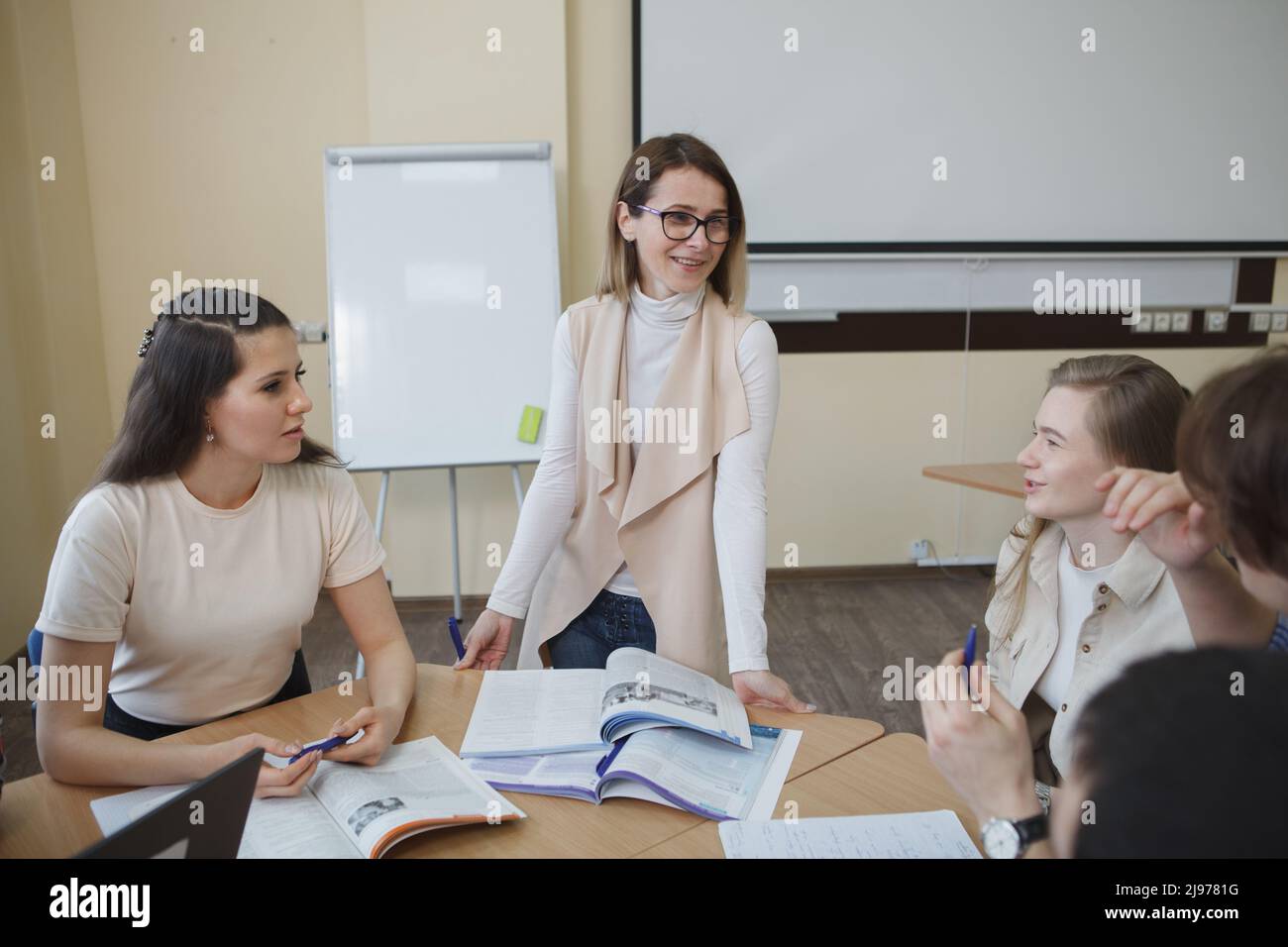 Glückliche, reife Lehrerin, die gerne mit Schülern arbeitet und freudig lächelt Stockfoto