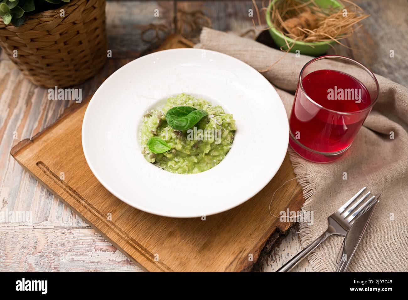 Servierplatte aus grünem Risotto mit Basilikumblättern und Käse. Gesunde Ernährung. Zartes arborio mit Spinatgemüse und mit Lammfleisch brot angereichert Stockfoto