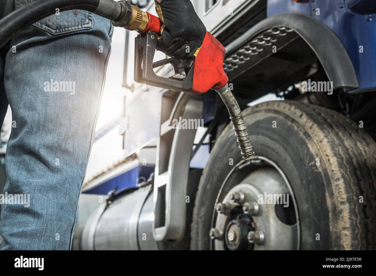 Gealterter Semi-Truck-Fahrer, der seinen Traktor mit der Dieselpumpendüse in der Hand betankt. Heavy Duty Transport and Fuel Knappheit Concept. Stockfoto
