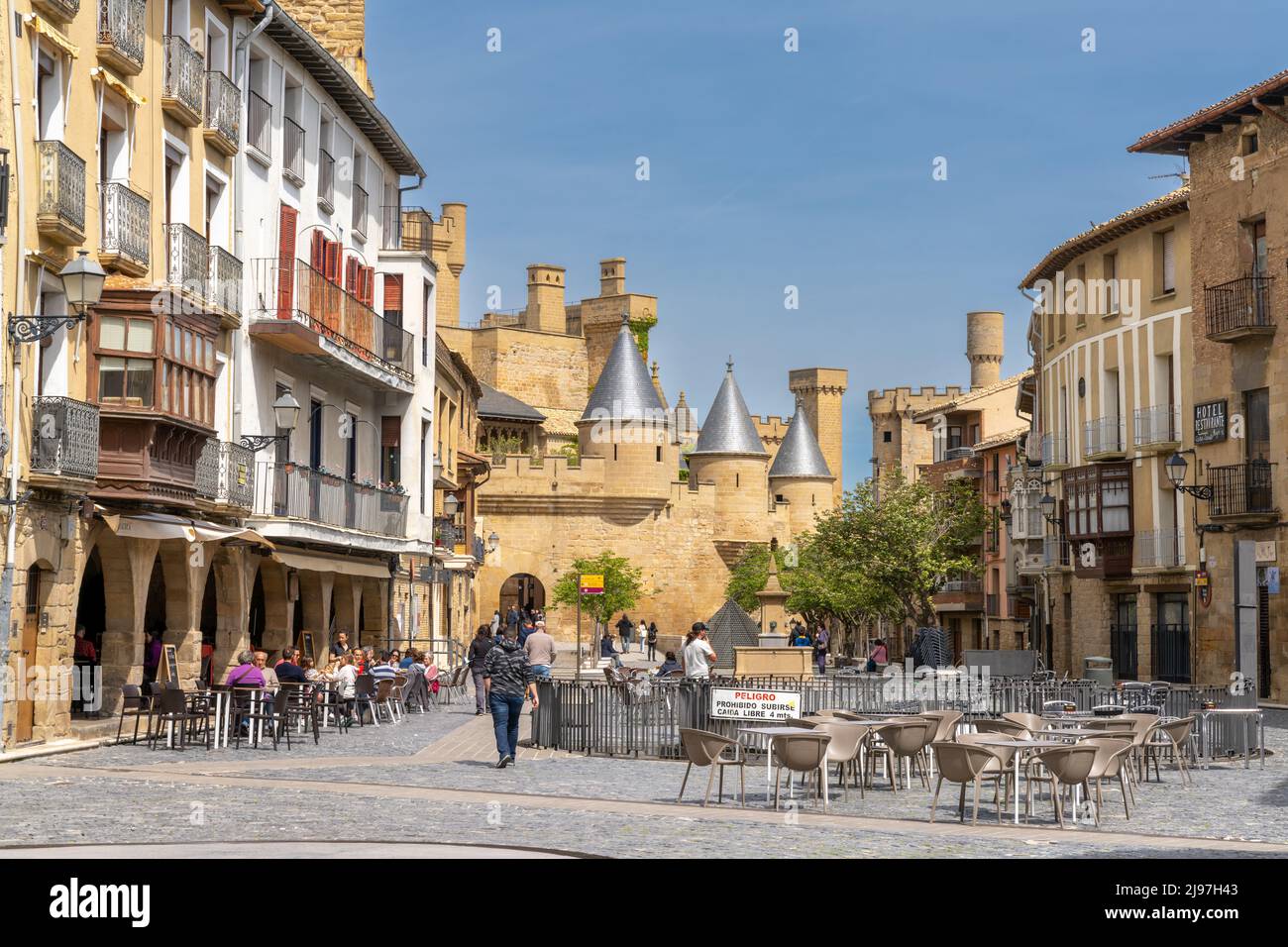 Olite, Spanien - 30. April 2022: Touristen genießen einen Besuch im historischen Olite an einem schönen Sommertag mit dem Palacio Real Schloss im Hintergrund Stockfoto