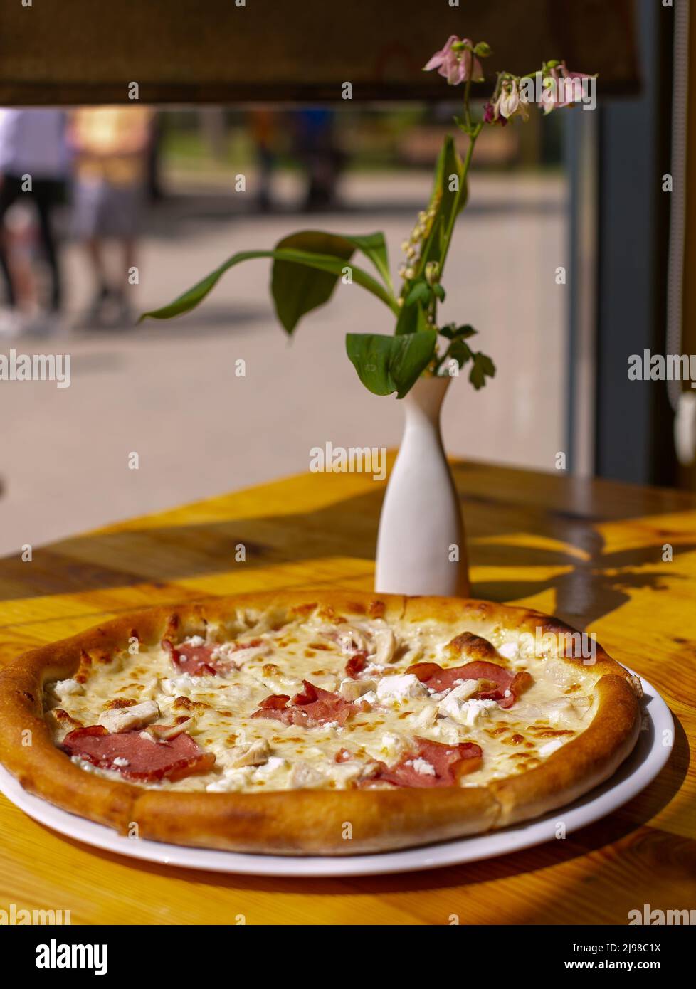 Pizza mit Sauce, Huhn, Käse auf dem Teller auf Holztisch serviert. Stockfoto