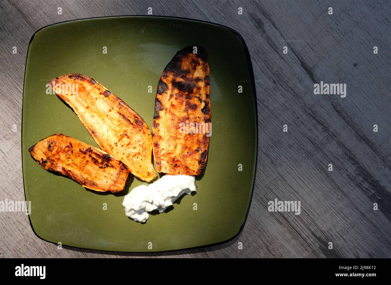Scheiben von köstlichen gegrillten Süßkartoffeln und Frischkäse - Sommer Barbecue vegetarisches Mittagessen auf grünen Teller Stockfoto