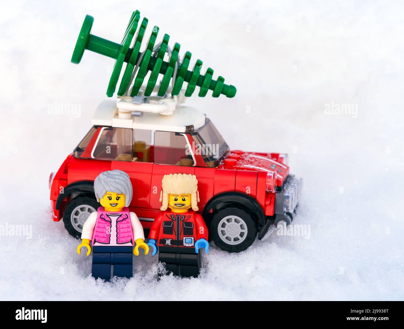 Tambow, Russische Föderation - 19. Januar 2022 zwei Lego-Minifiguren stehen vor einem roten Auto, auf dem ein Weihnachtsbaum steht. Schneehintergrund Stockfoto
