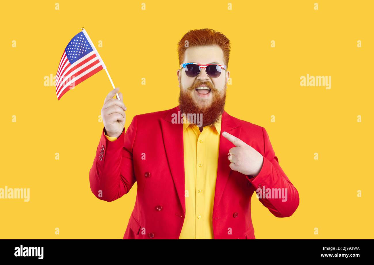 Ein lustiger, fetter Mann, der Amerikas Unabhängigkeitstag feiert, trägt eine patriotische Brille und hält die USA-Flagge. Stockfoto