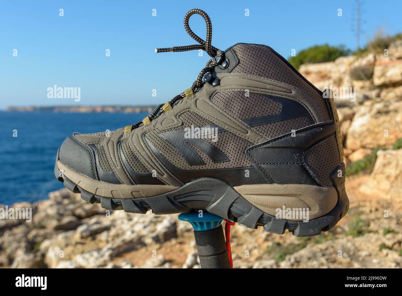 Olivgrüne Wanderschuhe auf einem natürlichen Hintergrund aus Meer und Felsen Stockfoto