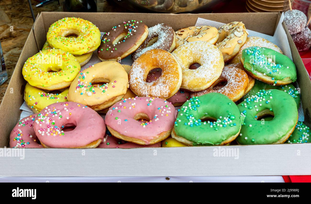 Runde leckere bunte Donuts in einer Pappschachtel. Leckere runde glasierte Kuchen Stockfoto