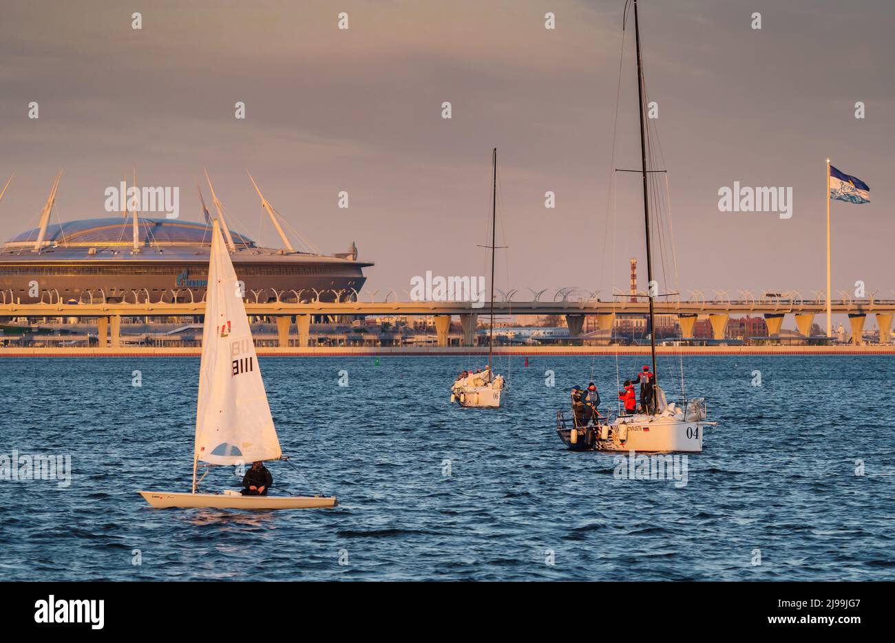 Russland, St. Petersburg, 20. Mai 2022: Segelboote im Hintergrund des neuen Stadions Gazprom Arena von der Ölgesellschaft Gazprom im Abendlicht Stockfoto