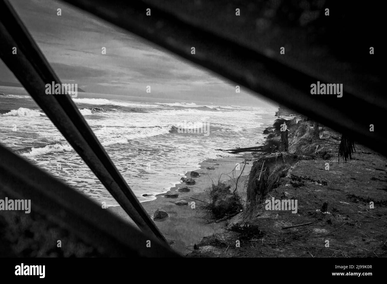 Südchinesische Meeresküste in Vietnam während eines Sturms, der aus der Abdeckung am Strand herausguckt. B&W. Stockfoto