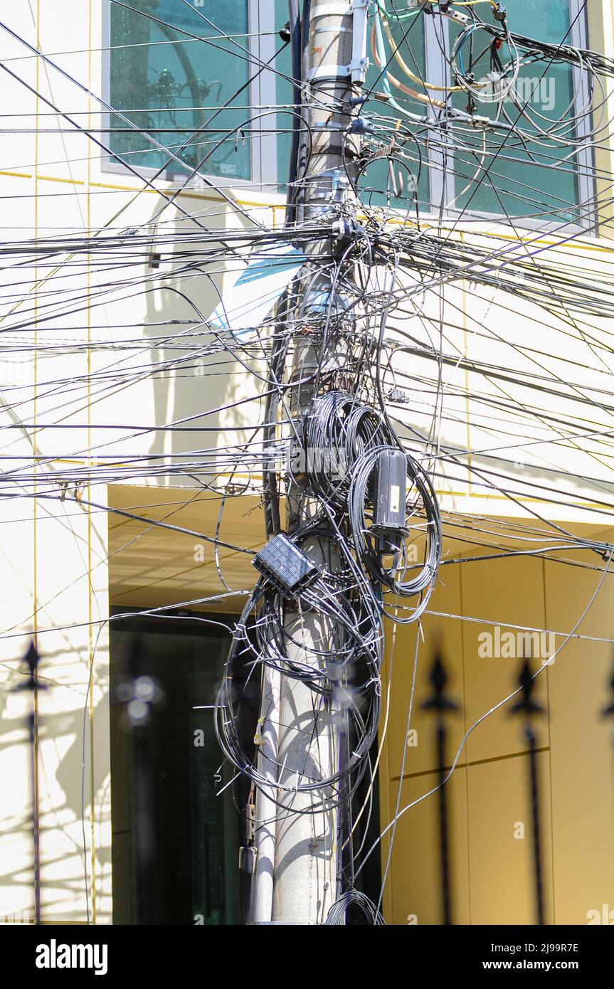 Unorganisierte schwarze und verworrene Glasfaser-Internet-Kommunikationskabel auf Betonmasten, die häufig auf den Straßen großer Städte in Rumänien zu finden sind Stockfoto