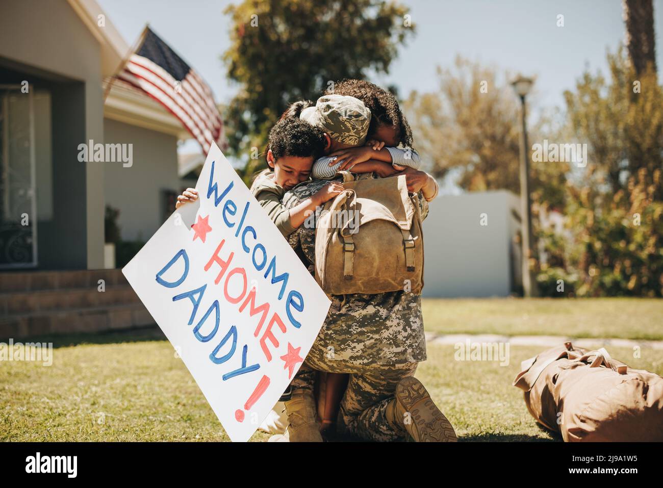 Militärangehöriger, der sich nach seiner Rückkehr aus der Armee wieder mit seiner Familie vereinigte. Amerikanischer Soldat umarmt Frau und Kinder im Freien. Militärangehöriger empfängt Stockfoto