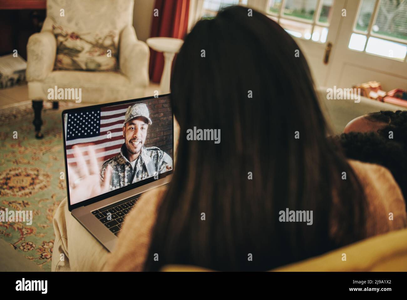 Amerikanischer Soldat, der während der Feiertage seine Familie anruft. Militärangehöriger, der mit seiner Familie auf einem Laptop kommuniziert. Militärische Familie mit einem Online Stockfoto