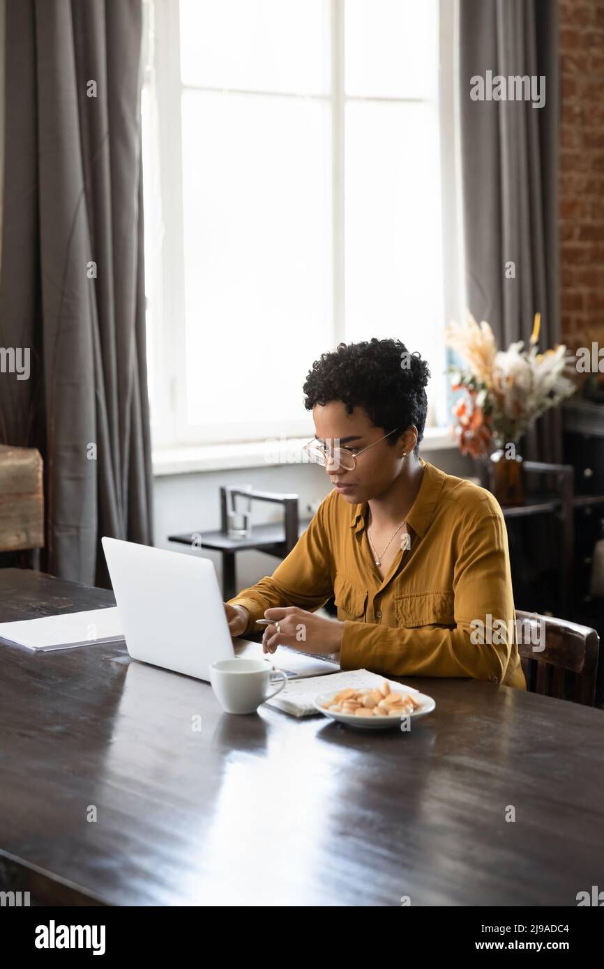 Ernsthafte afrikanische Frau, die mit einem Laptop arbeitet oder studiert Stockfoto