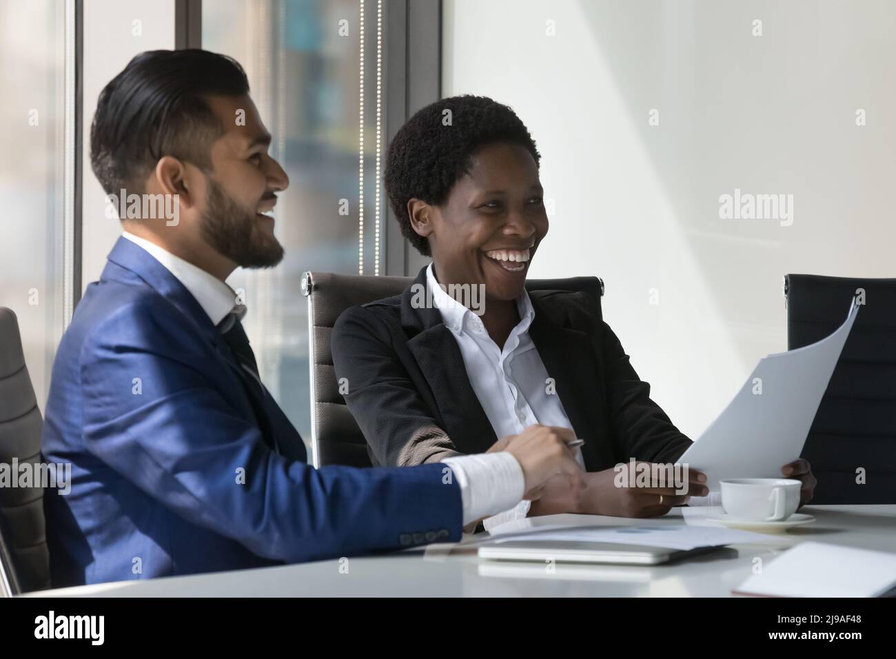 Zwei glückliche multirassische Arbeitskollegen lachen Brainstorming diskutieren Ideen bei der Sitzung Stockfoto