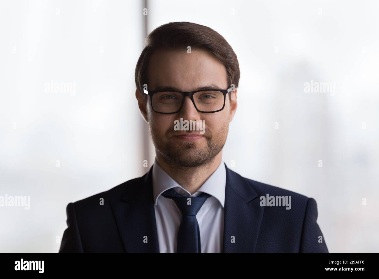 Kopfschuss Porträt gutaussehender Millennial Geschäftsmann in formellen Anzug posiert drinnen Stockfoto