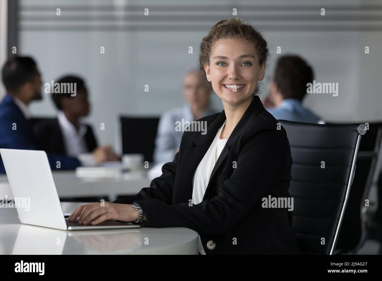 Eine erfolgreiche Geschäftsfrau sitzt am Schreibtisch, während der Laptop die Kamera anschaut Stockfoto