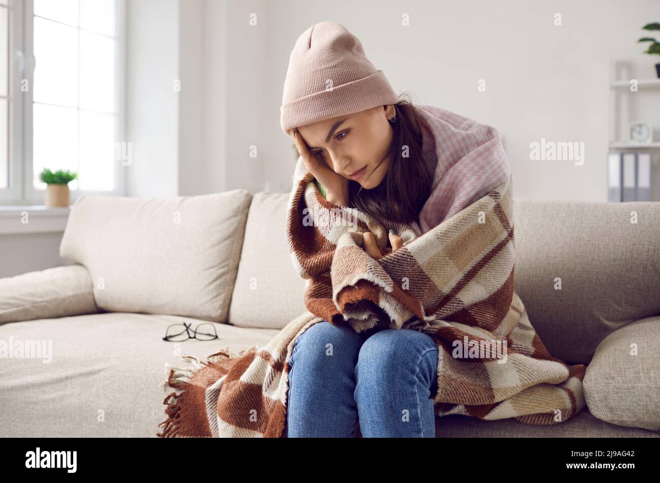 Die Frau in der warmen Decke friert wegen Fieber oder Problemen mit der Zentralheizung Stockfoto